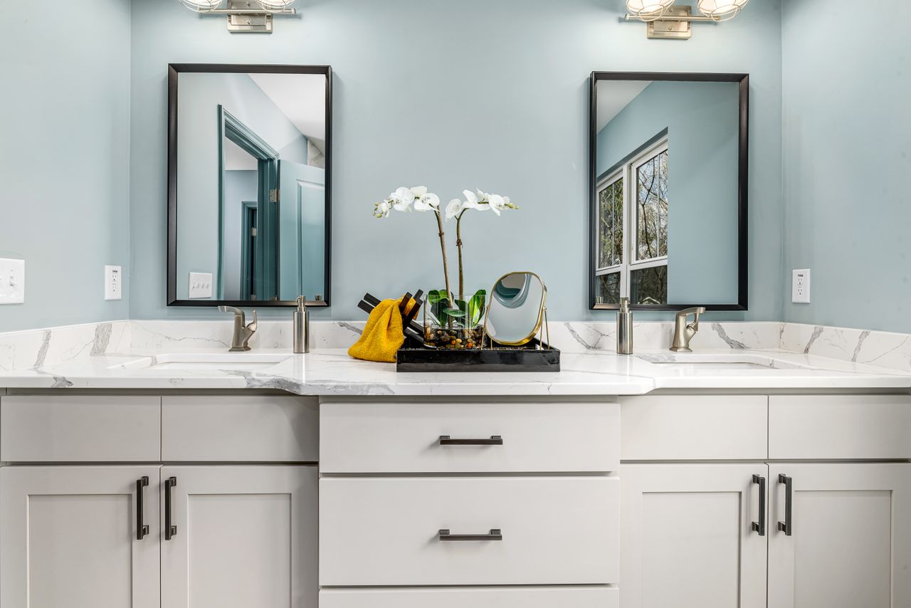 A serene modern bathroom featuring twin sinks, elegant faucets, and decorative mirrors.