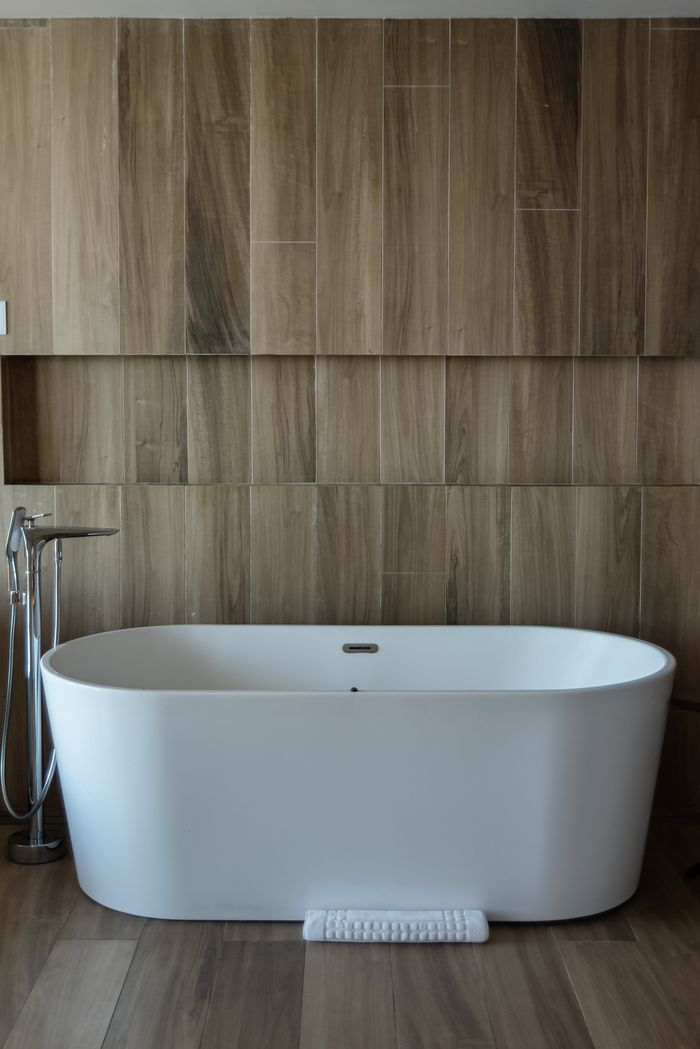 A stylish white bathtub in a contemporary spa-like bathroom with wooden decor.