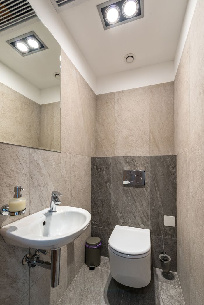 White ceramic sink and toilet bowl in modern bathroom with tiled walls and mirror