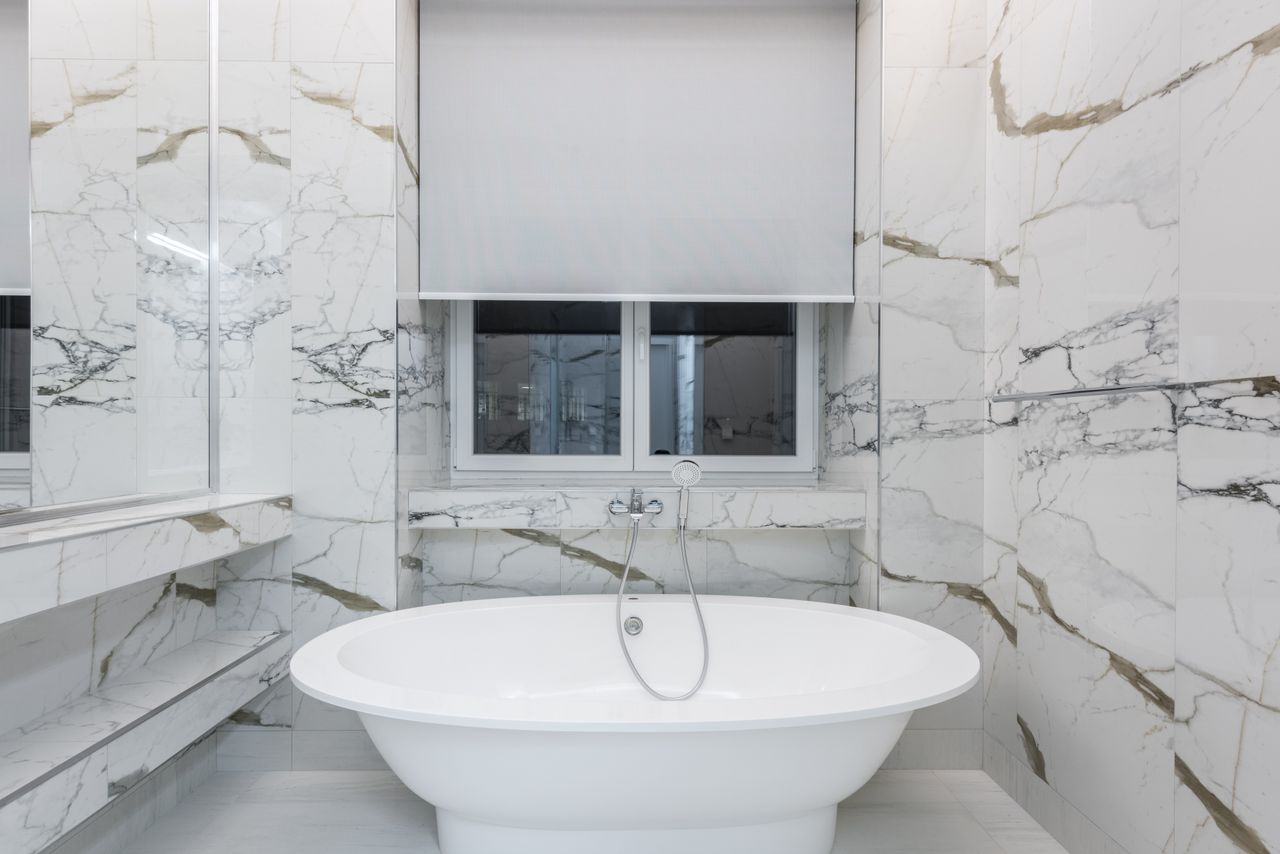Modern bathroom featuring a luxurious marble design and a sleek freestanding bathtub.